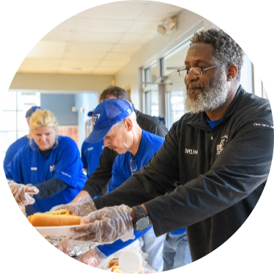 Several Reynolds American employees standing behind a table and passing out food at the United Way Days of Caring.