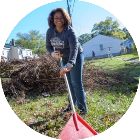 shay_mustafa Reynolds American employee holding raking leaves during a corporate philanthropy volunteer day.