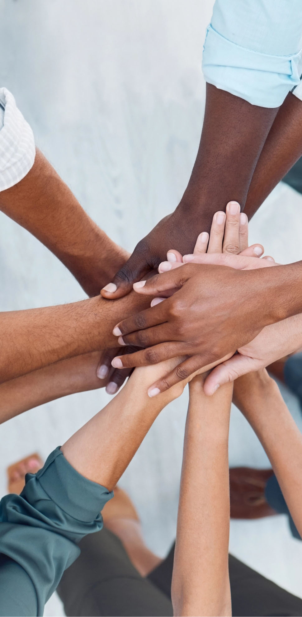 Close-up of diverse group of people all stacking hands, representing collaboration for youth access prevention programs.