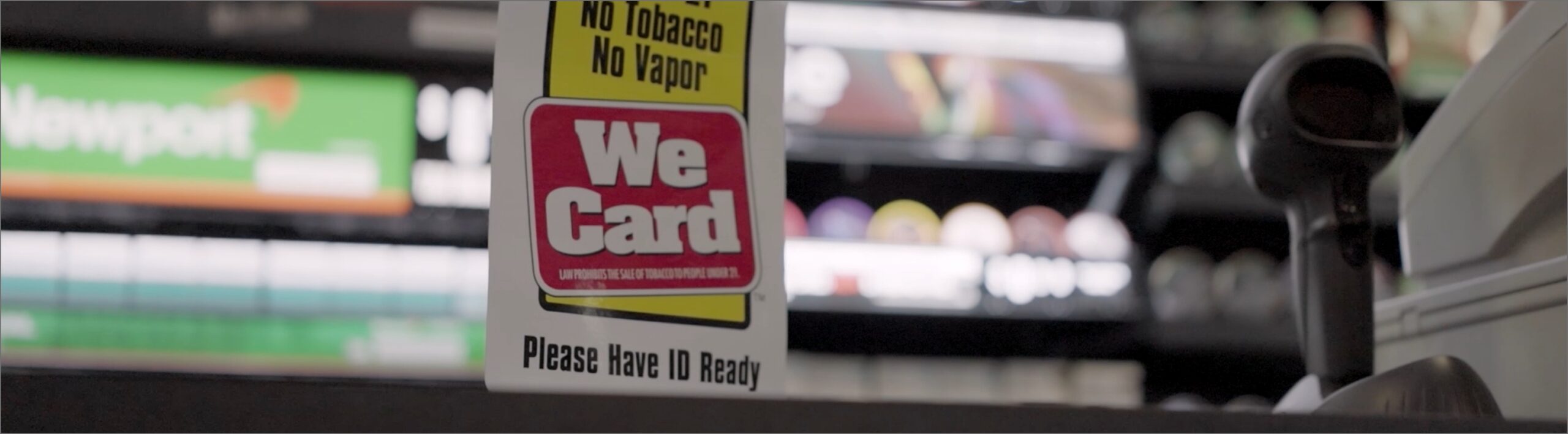 We Card logo sign in the window of a store, representing youth tobacco and nicotine youth access prevention.